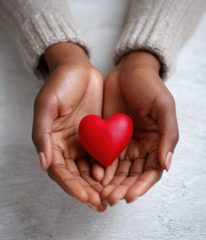 health medicine and charity concept  close up of african american female hands with small red heart no logos no brands ar 34